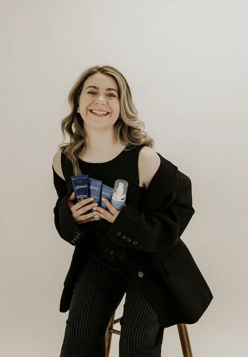 Emily Keith, founder of EmGlowSkin, holding professional skincare products